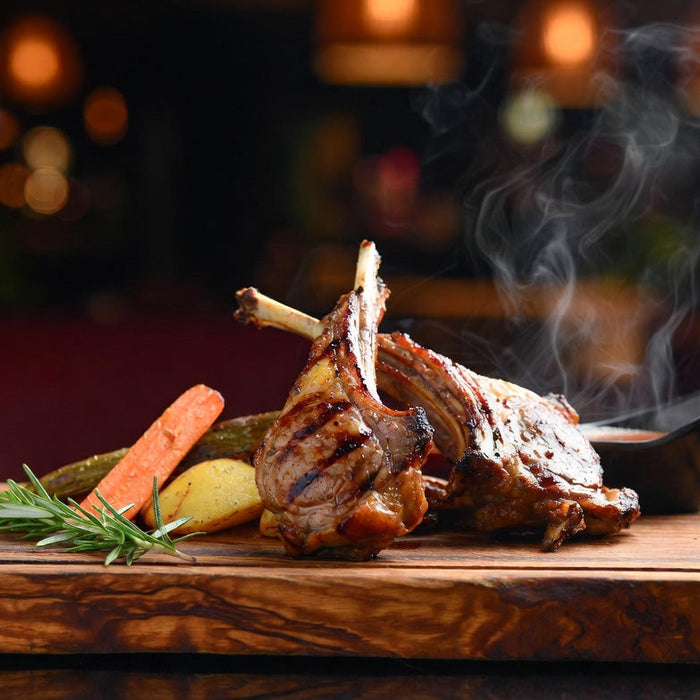 Grilled lamb chops on wooden board with rosemary and vegetables