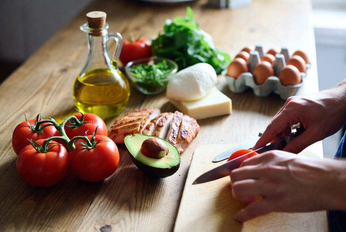 Fresh tomatoes with keto-friendly foods on a healthy meal prep counter