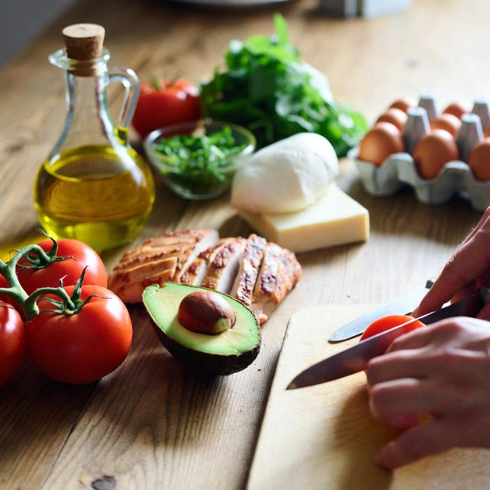 Fresh tomatoes with keto-friendly foods on a healthy meal prep counter