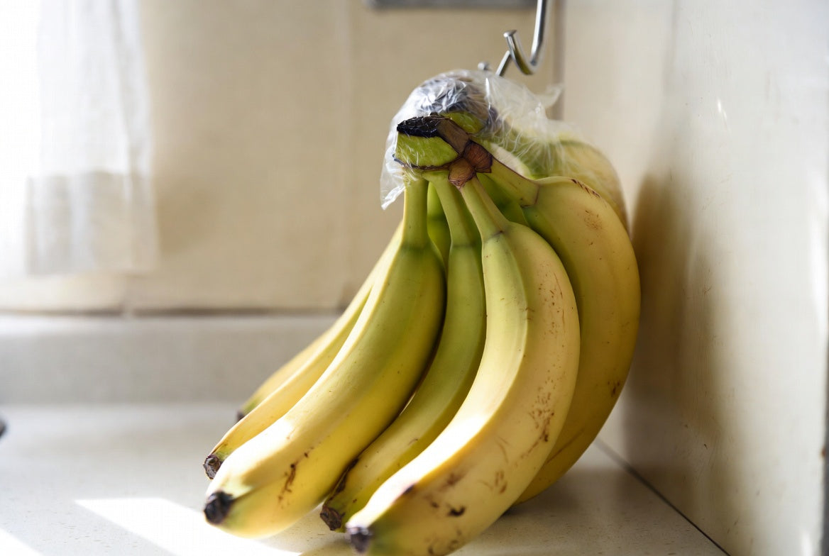 Bananas hanging with wrapped stems to help keep them fresh longer