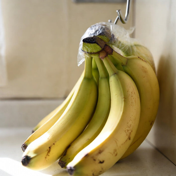 Bananas hanging with wrapped stems to help keep them fresh longer