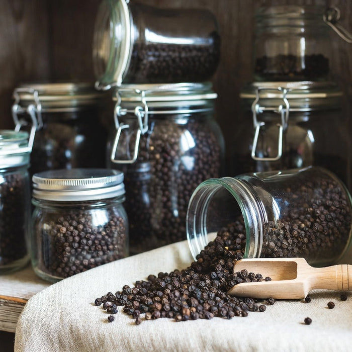 Glass jars filled with black peppercorns on rustic pantry shelf