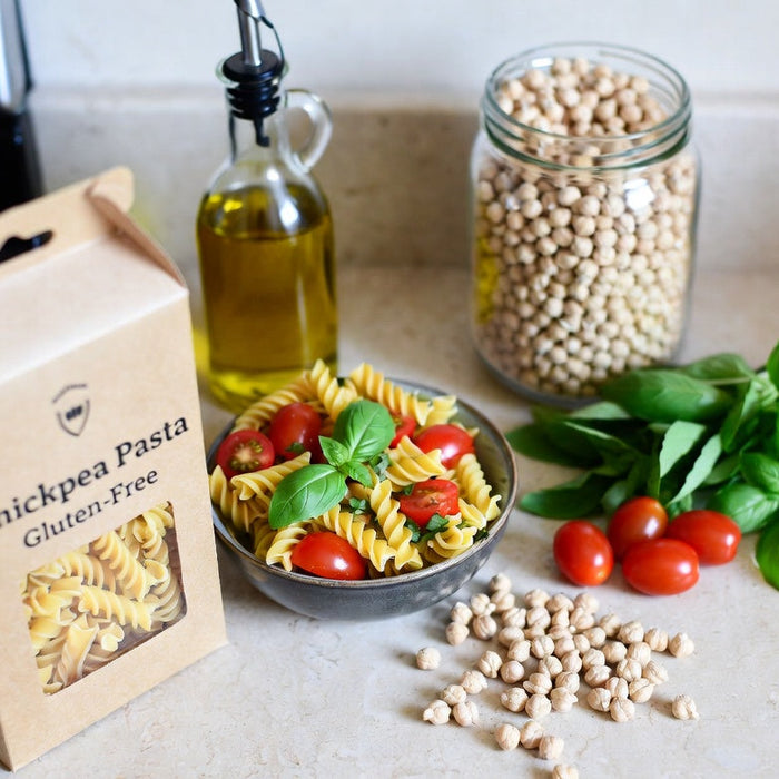 Chickpea pasta box with basil, tomatoes, and dry chickpeas on counter  Jars