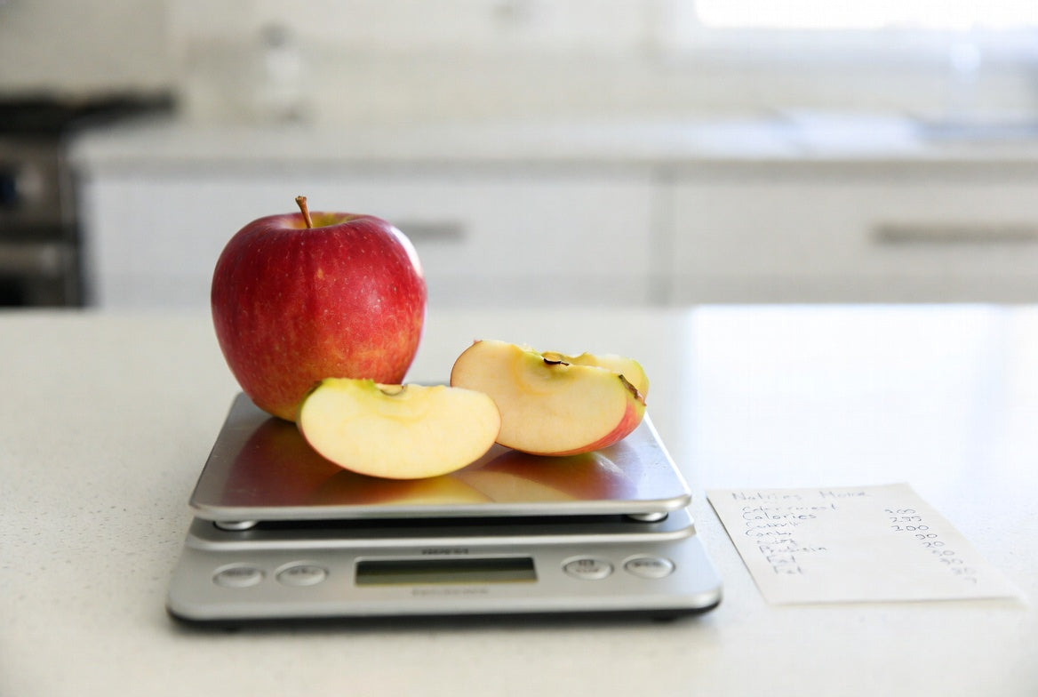 Apple and slices on kitchen scale with nutrition note