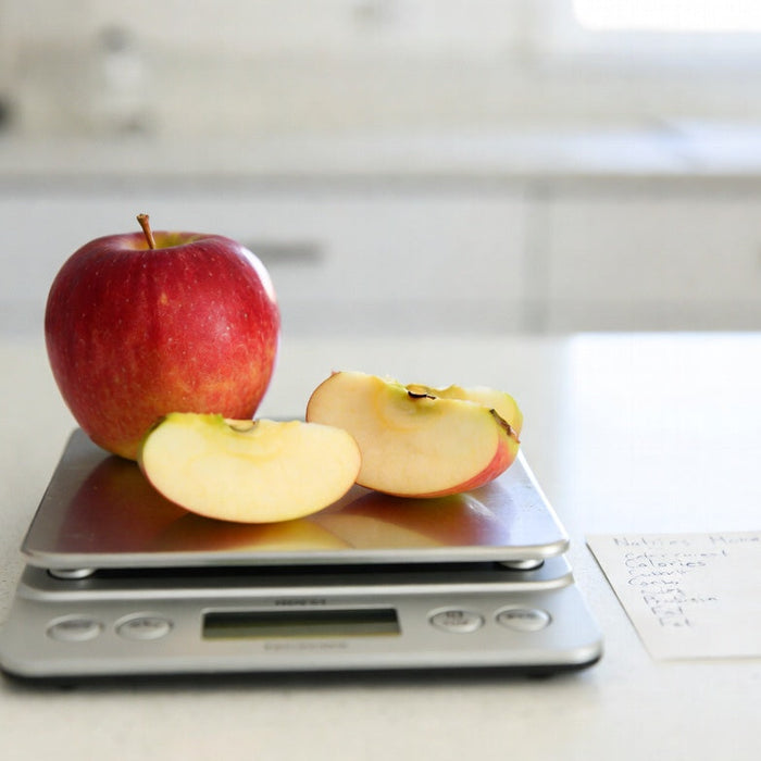 Apple and slices on kitchen scale with nutrition note