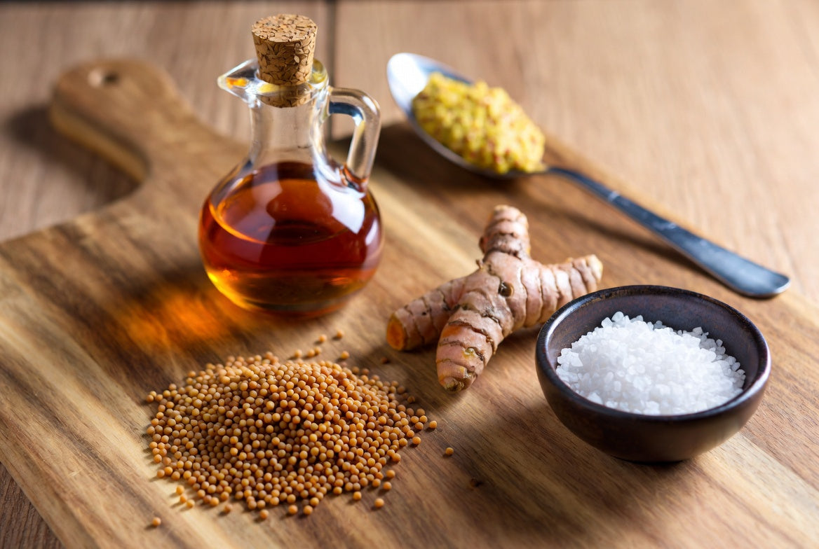Mustard seeds, vinegar, turmeric, and salt on wooden board