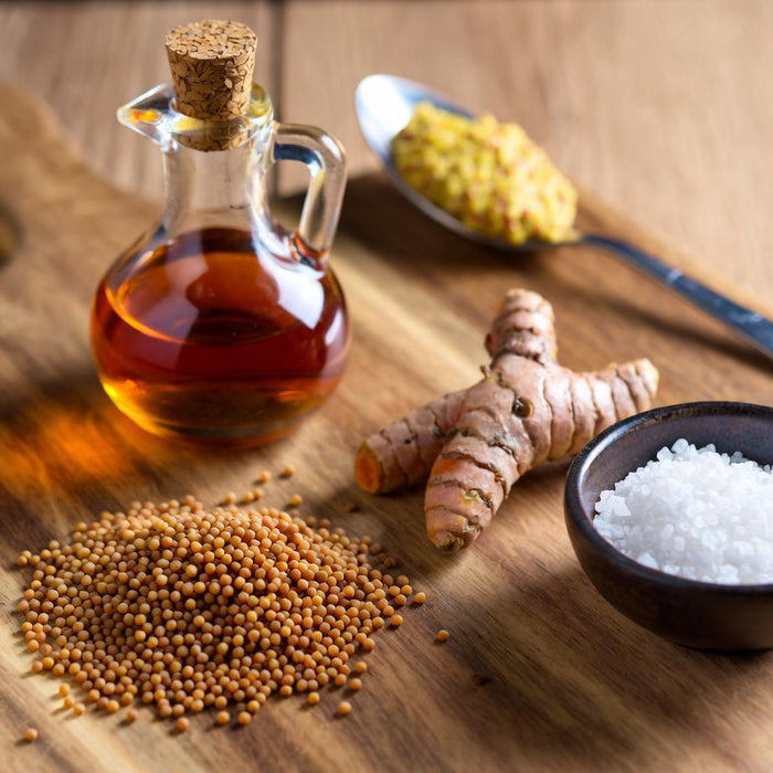 Mustard seeds, vinegar, turmeric, and salt on wooden board
