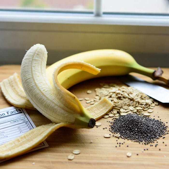 Peeled banana with oats, chia seeds, and nutrition card on cutting board
