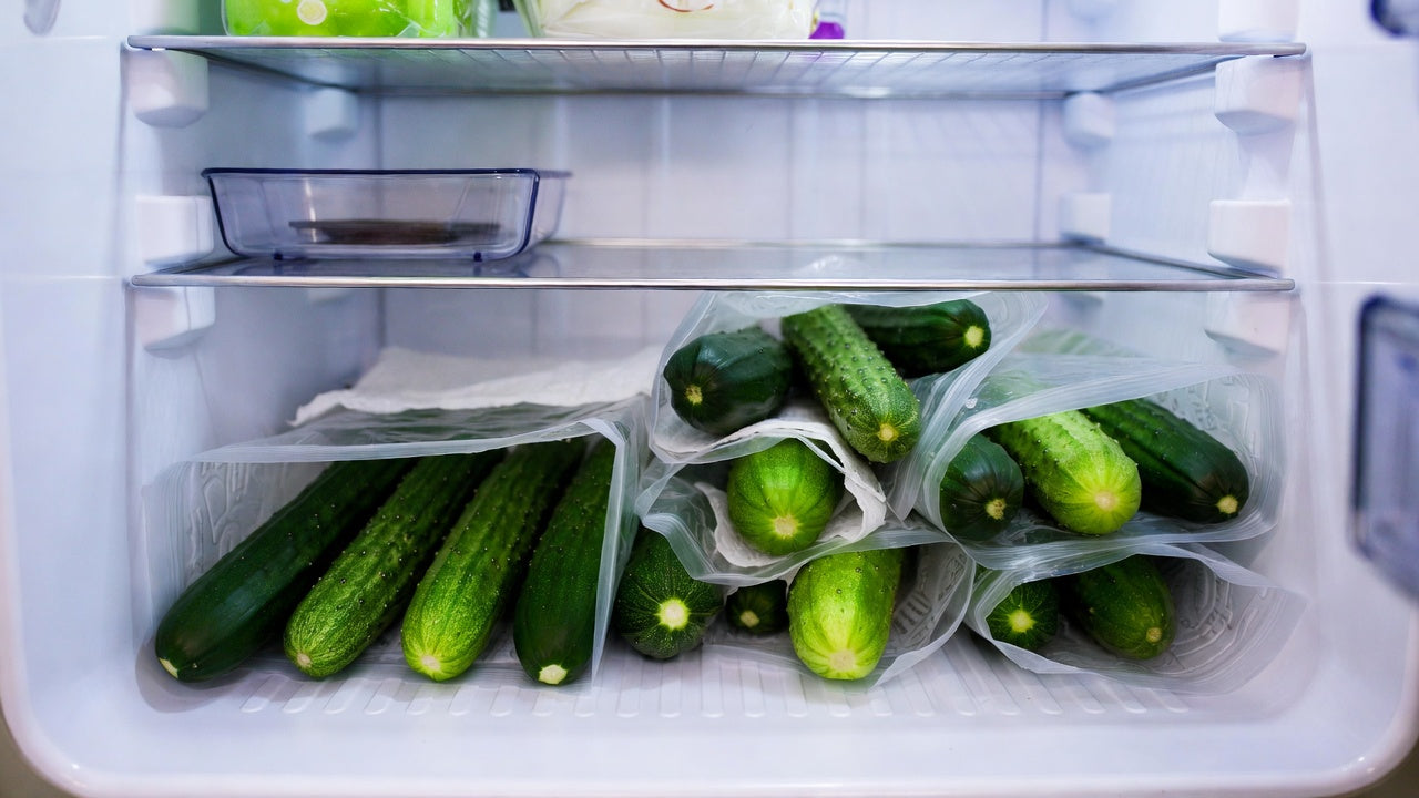 Fresh cucumbers stored in reusable bags inside a refrigerator drawers
