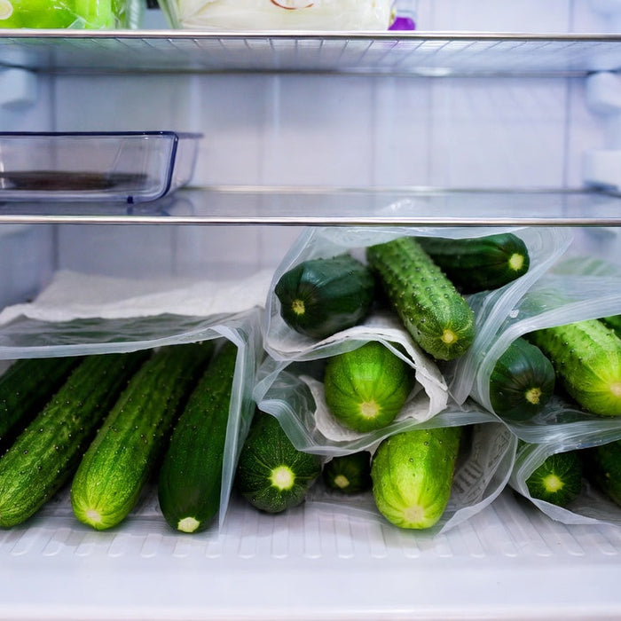 Fresh cucumbers stored in reusable bags inside a refrigerator drawers