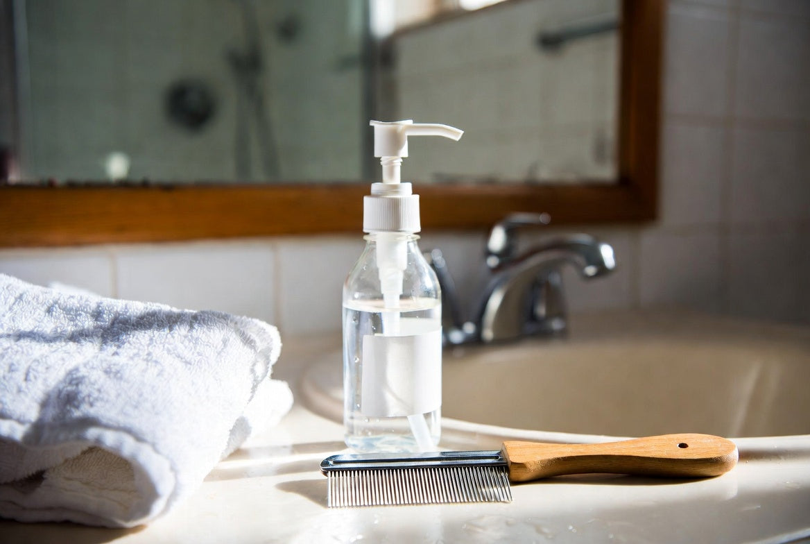 Vinegar bottle and lice comb on bathroom sink beside folded towel