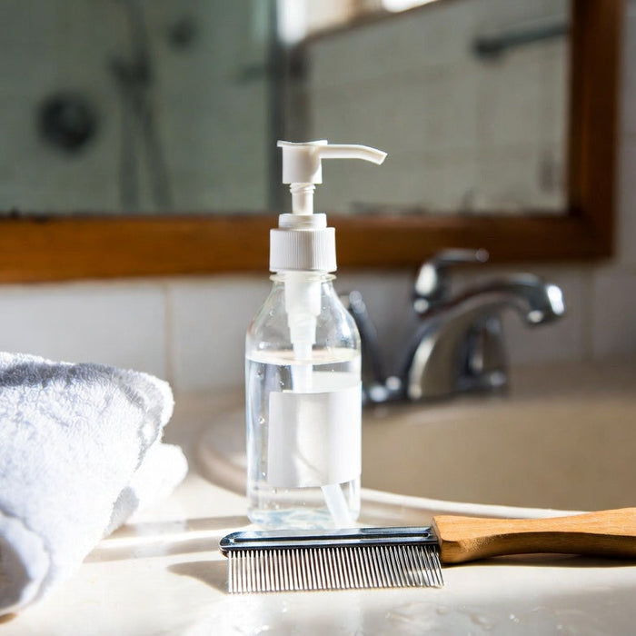 Vinegar bottle and lice comb on bathroom sink beside folded towel