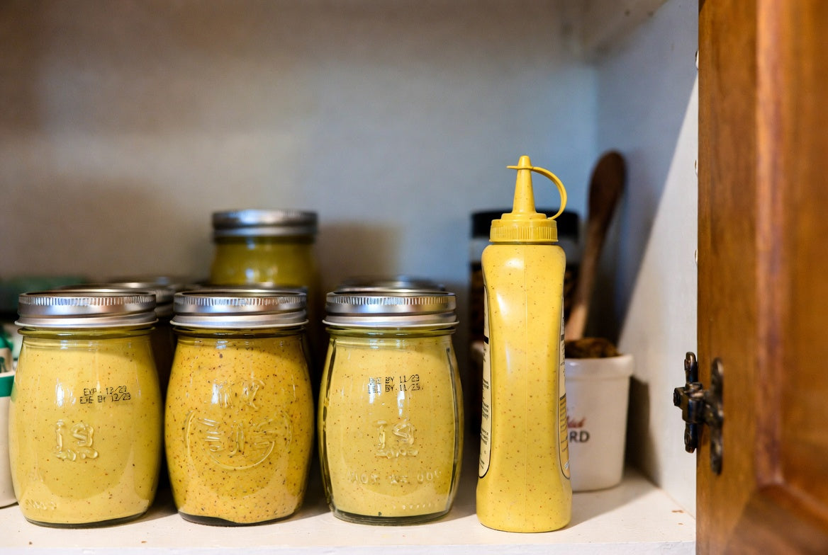 Mustard jars and squeeze bottle stored on pantry shelf