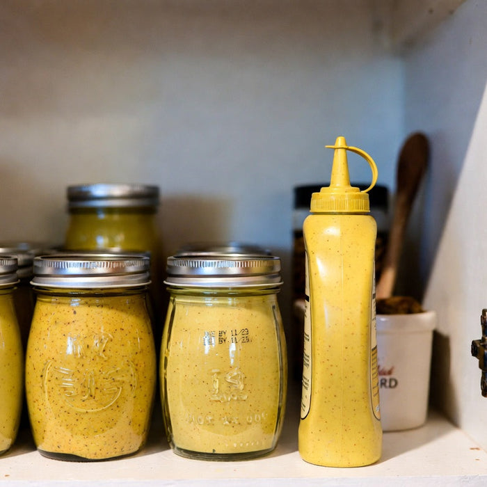 Mustard jars and squeeze bottle stored on pantry shelf