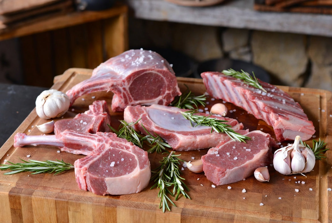 Raw lamb cuts with rosemary, garlic and salt on butcher block