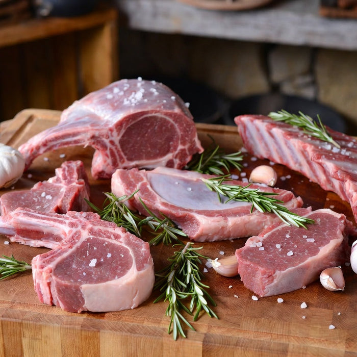 Raw lamb cuts with rosemary, garlic and salt on butcher block
