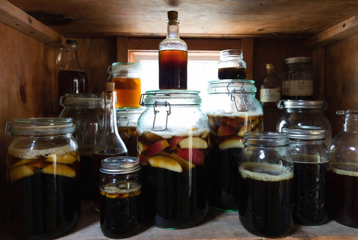 Pantry shelf filled with jars of fermenting homemade fruit vinegar