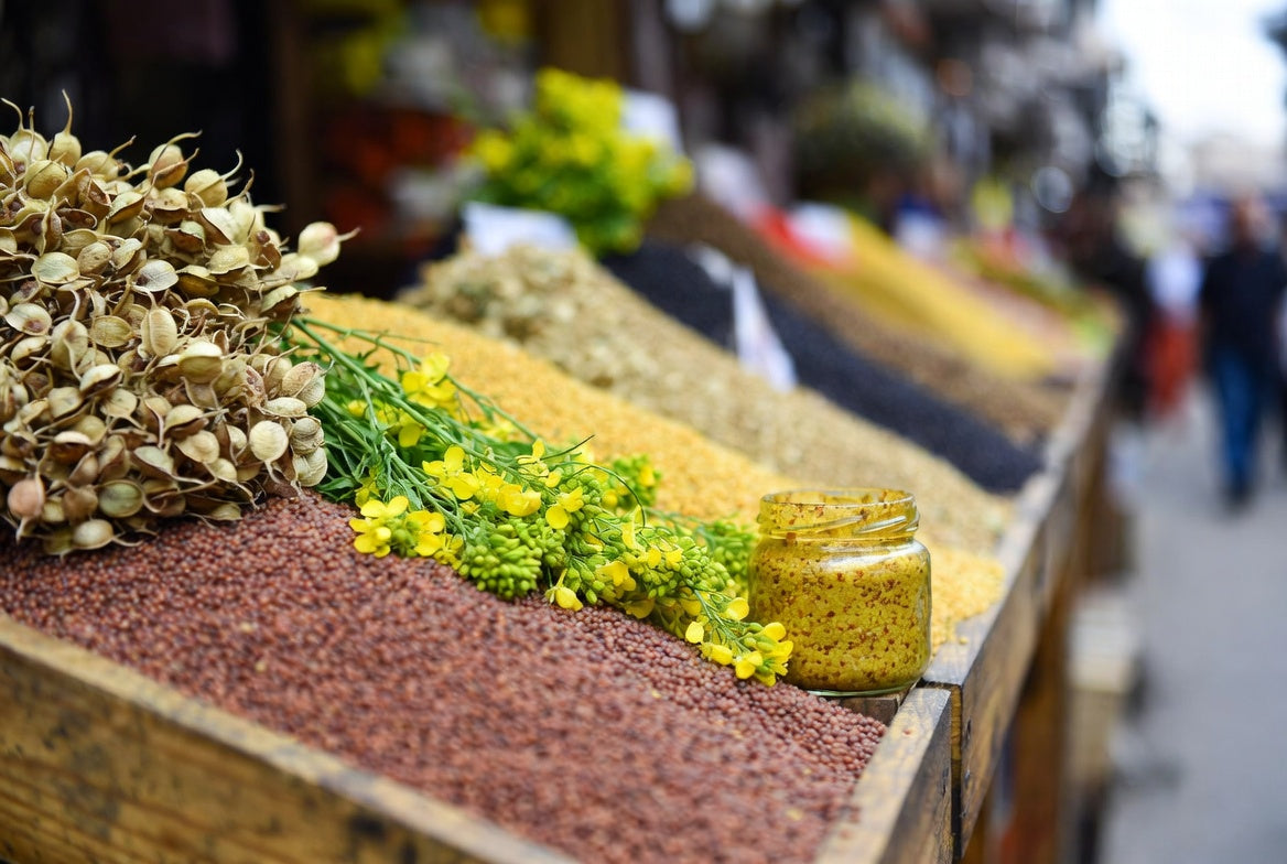 Mustard jar with seeds and flowers at rustic market display