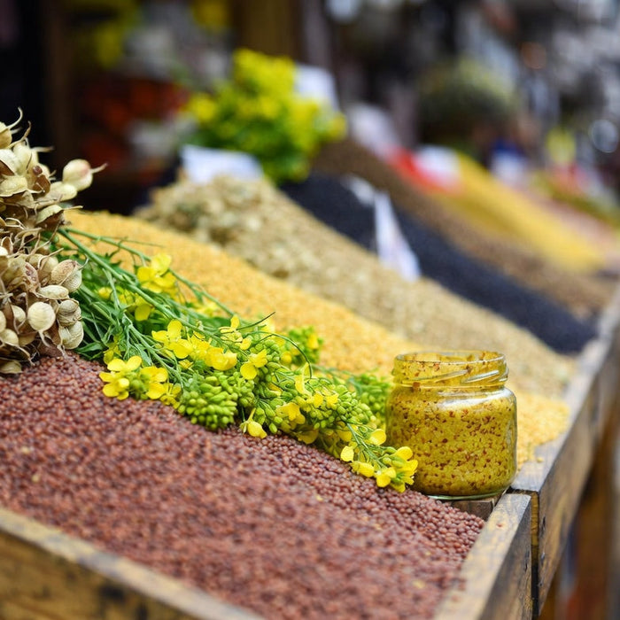 Mustard jar with seeds and flowers at rustic market display
