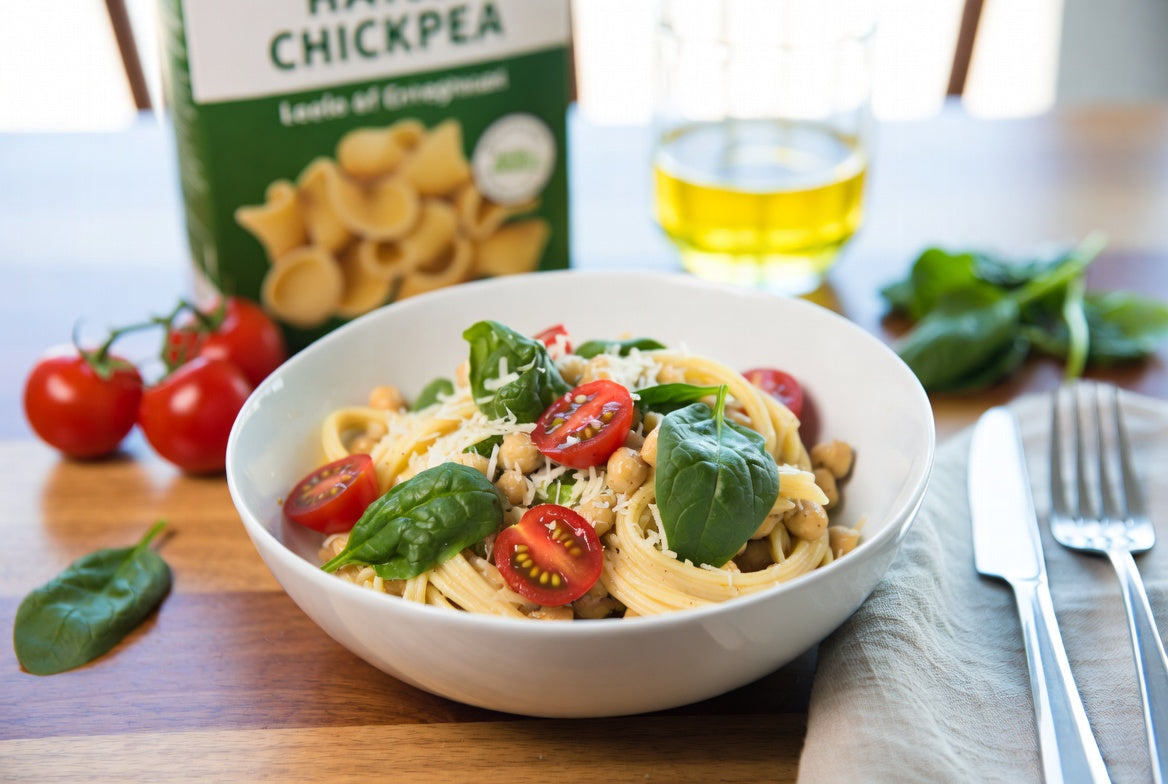 Chickpea pasta with tomatoes, basil, and chickpeas in white bowl