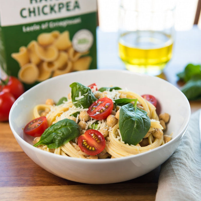 Chickpea pasta with tomatoes, basil, and chickpeas in white bowl