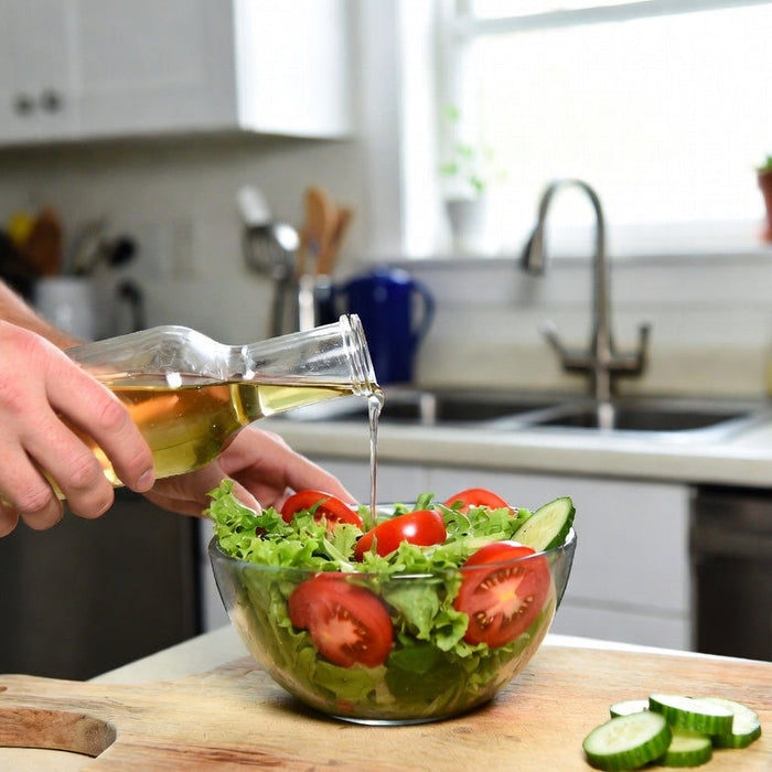 Hand pouring vinegar over fresh salad in a bright home kitchen scene.
