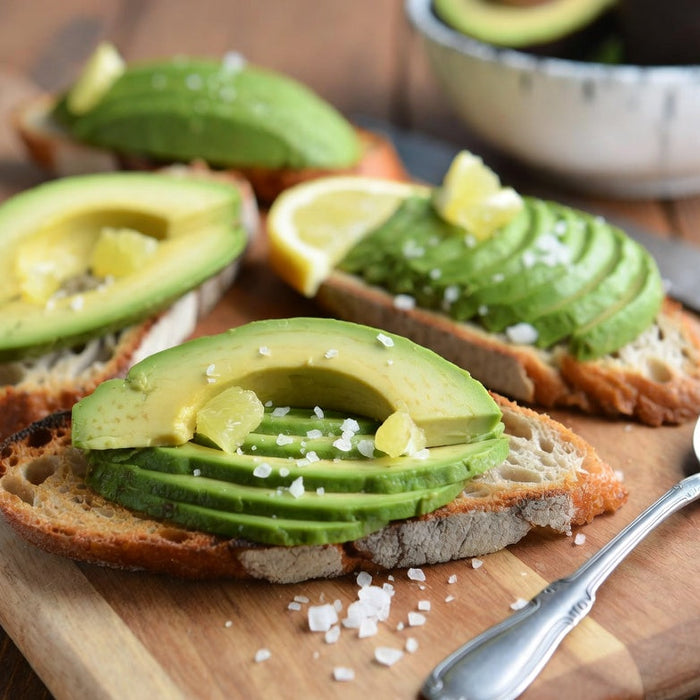 Avocado toast with lemon and salt on rustic wooden board