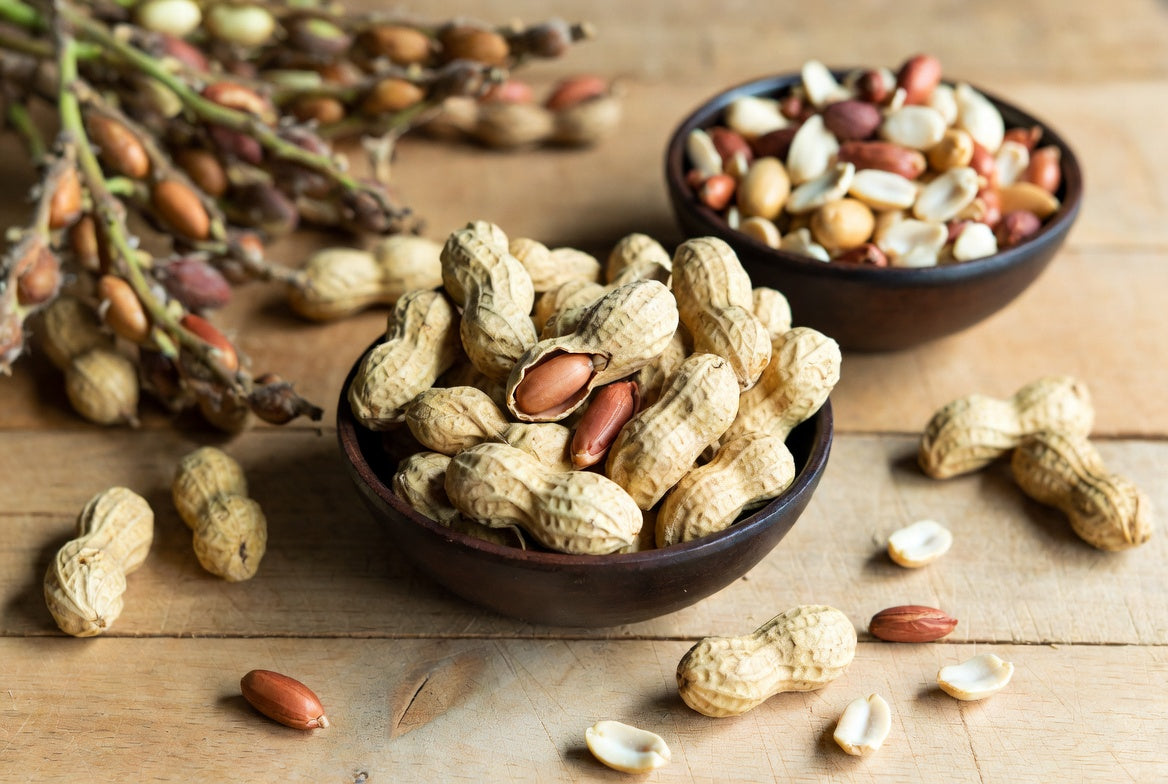 Bowl of peanuts in shells with mixed nuts on a rustic table