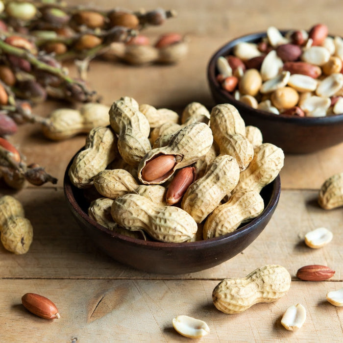 Bowl of peanuts in shells with mixed nuts on a rustic table