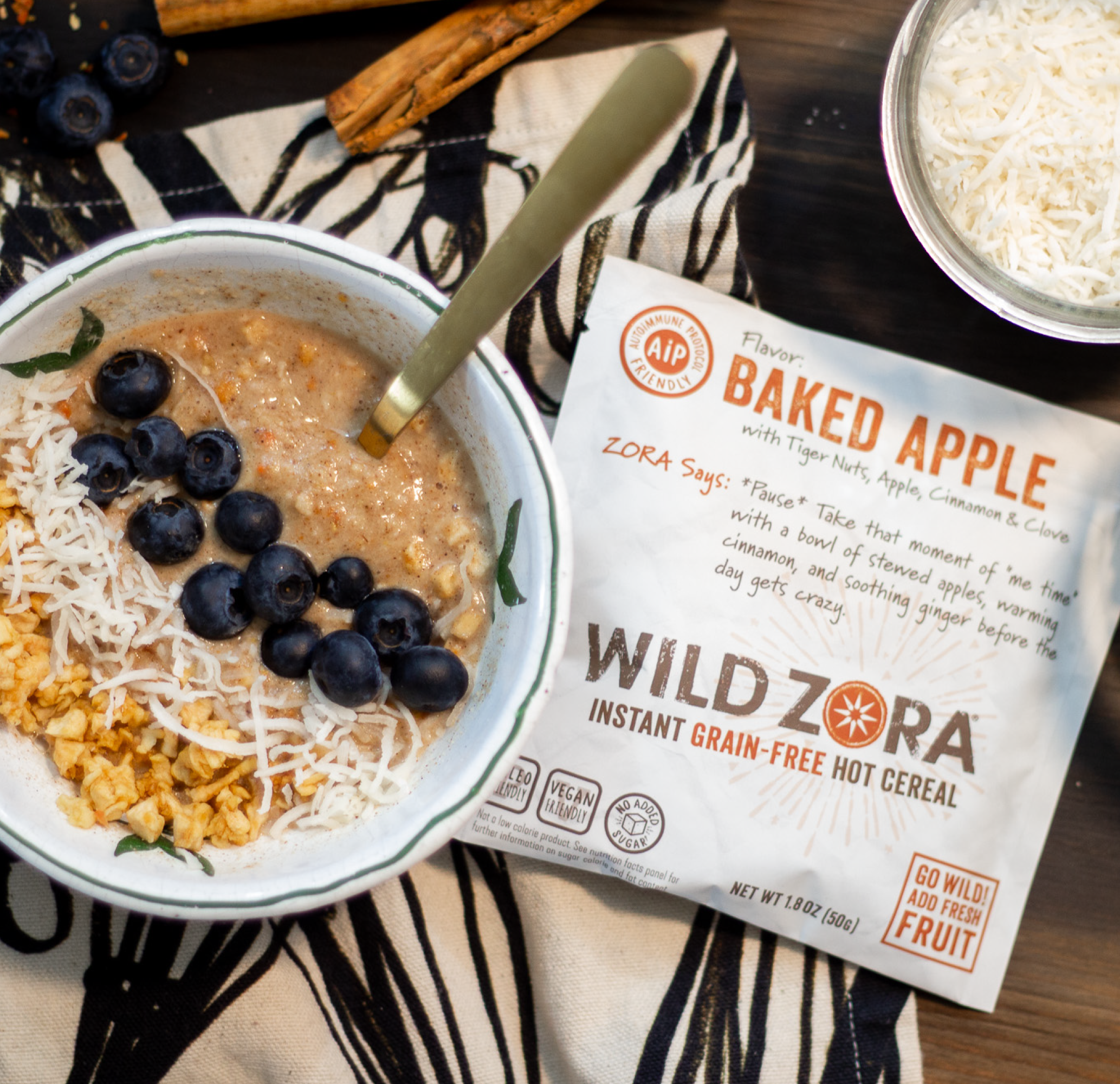 Wild Zora AIP Baked Apple Hot Cereal in a bowl with blueberries, coconut, and dried apple. Delicious & nutritious!